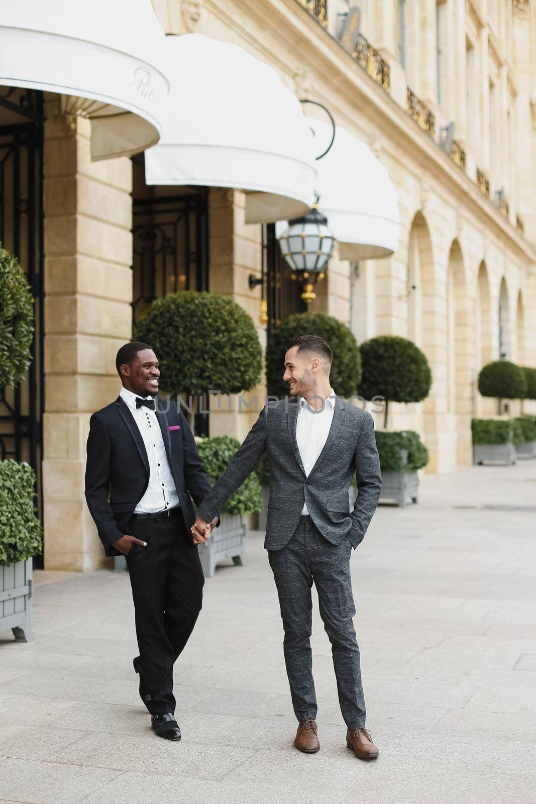 Afro american and caucasian stylish gays walking outside in city. Concept of same sex male couple.