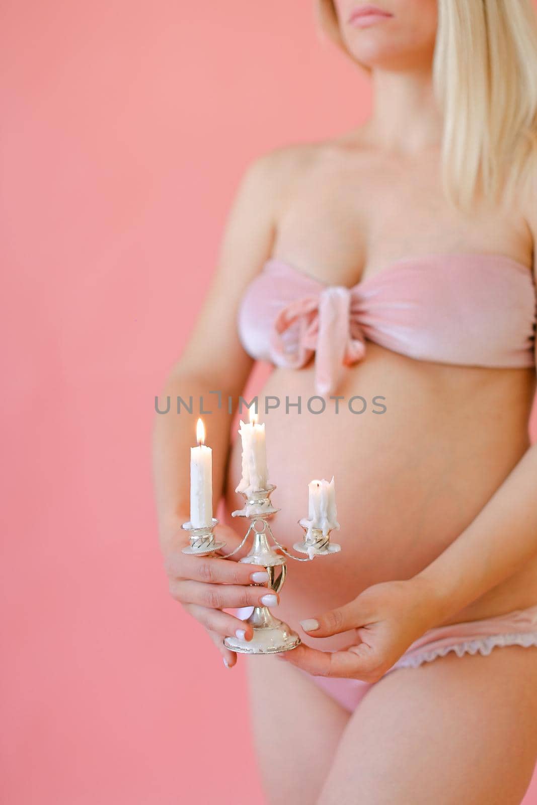 Young happy pregnant woman in underwear holding belly and keeping candles. by sisterspro