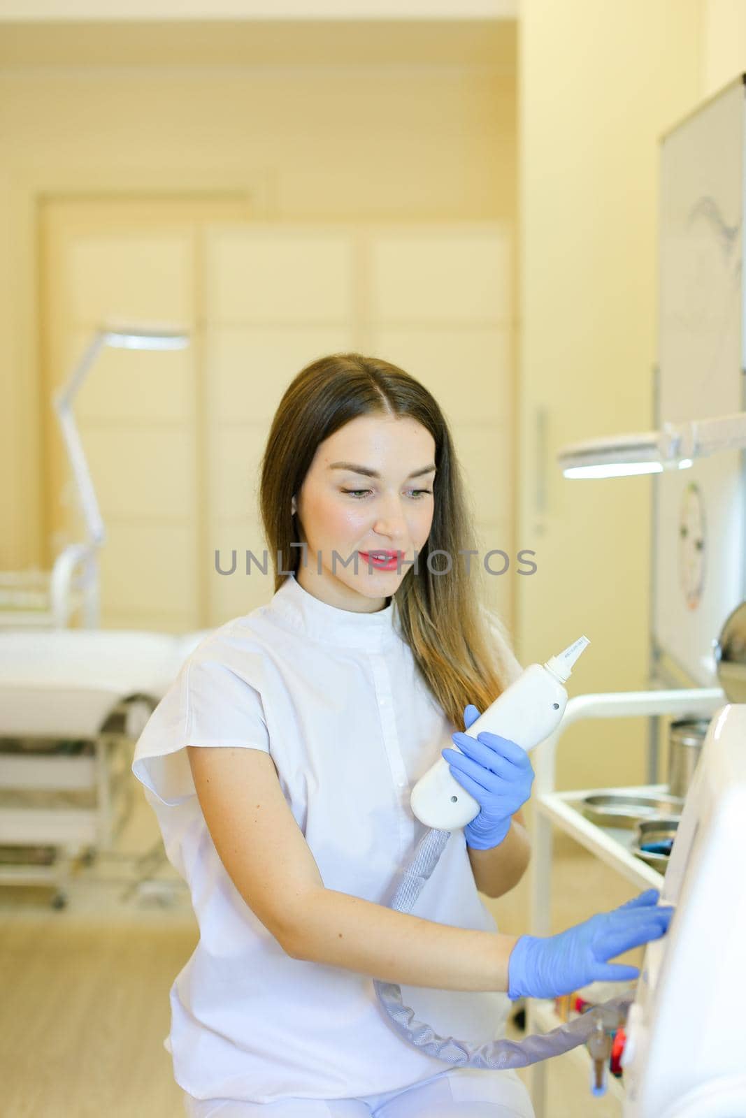 Young permanent makeup artist sitting with laser removal of tatoos device at beauty salon. Concept of cosmetology equipment and cosmetologist.