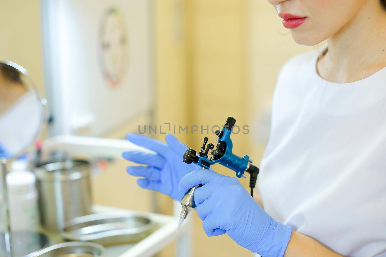 Close up cosmetlogist hands in blue latex gloves keeping microblading machine at beauty salon. by sisterspro