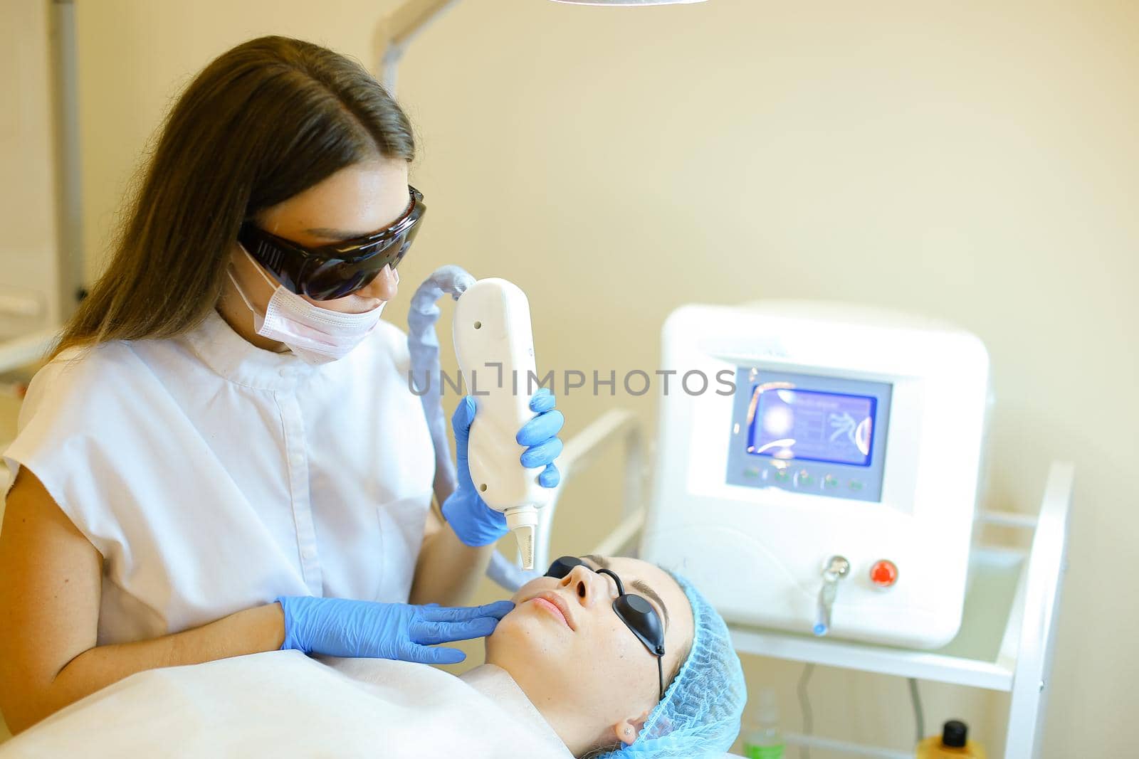 Skilled cosmetologist removing permanent makeup with laser for young girl at beauty salon. Concept of cosmetology equipment, special procedure before microblading.