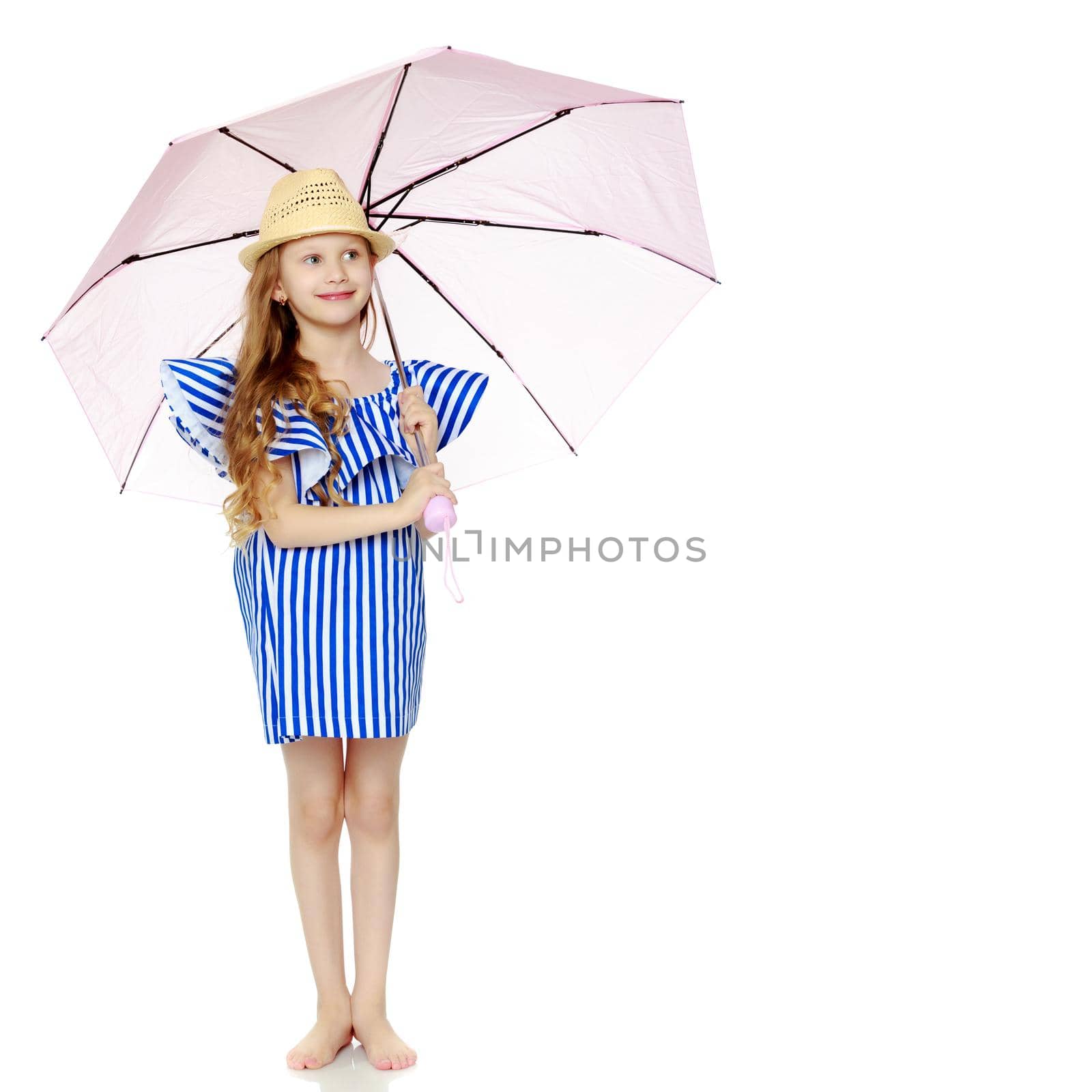 A stylish little girl with long blond hair in a very short, striped, summer blue dress and a straw hat.With a pink umbrella behind her shoulders.Isolated on white background.