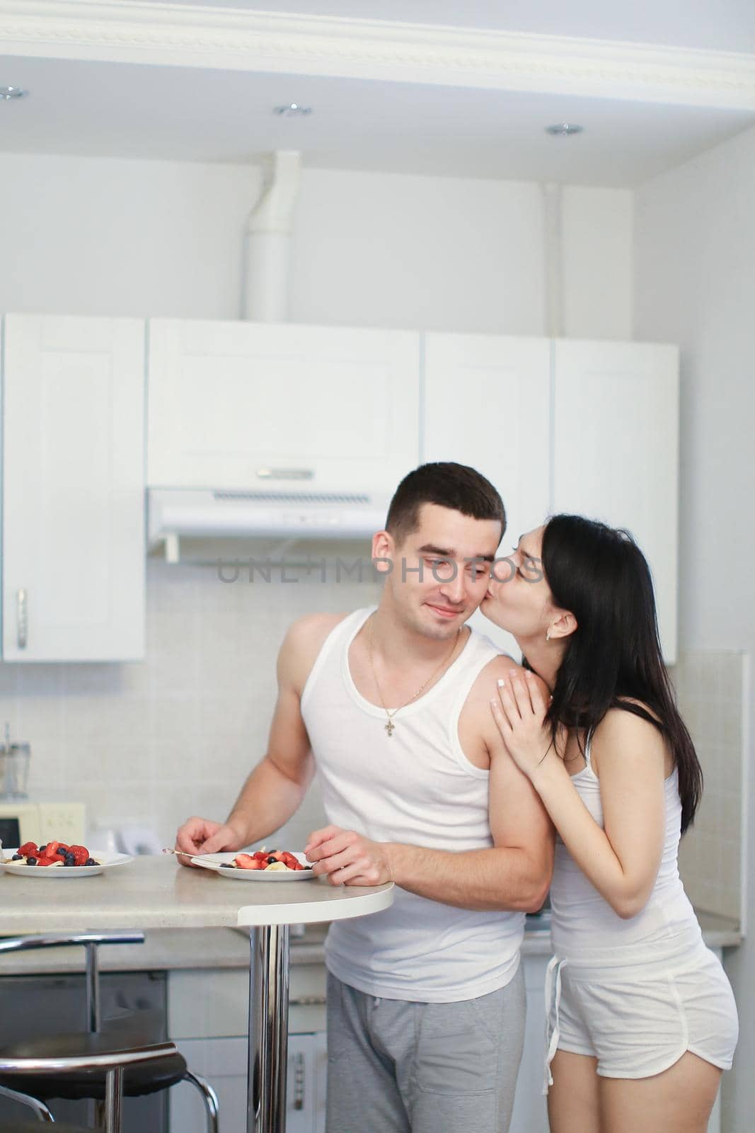 Boy and girl preparing breakfat in morning on kitchen, wearing t shirts. Concept of happy couple and tasty food, cooking and being together.