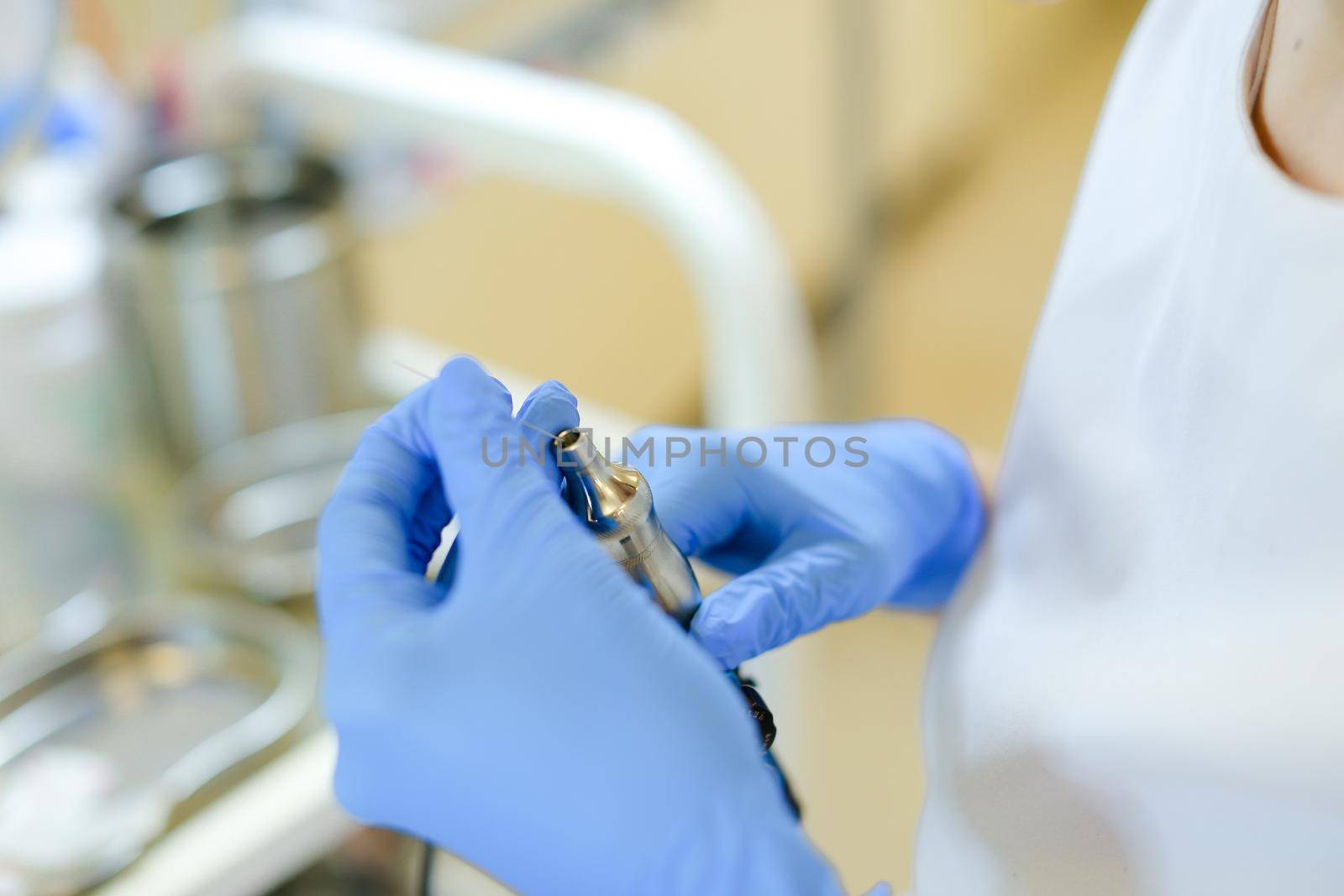 Closeup hands in latex gloves inserting needle into microblading device at beauty salon. Concept of cosmetology equipment for permanent makeup.