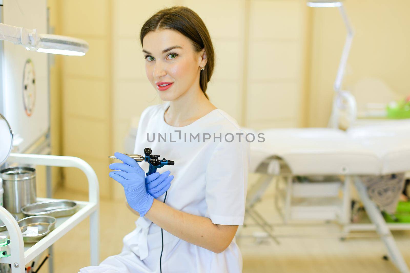 Young cosmetlogist standing with microblading machine at beauty salon. Concept of permanent makeup artist and cosmetology equipment.