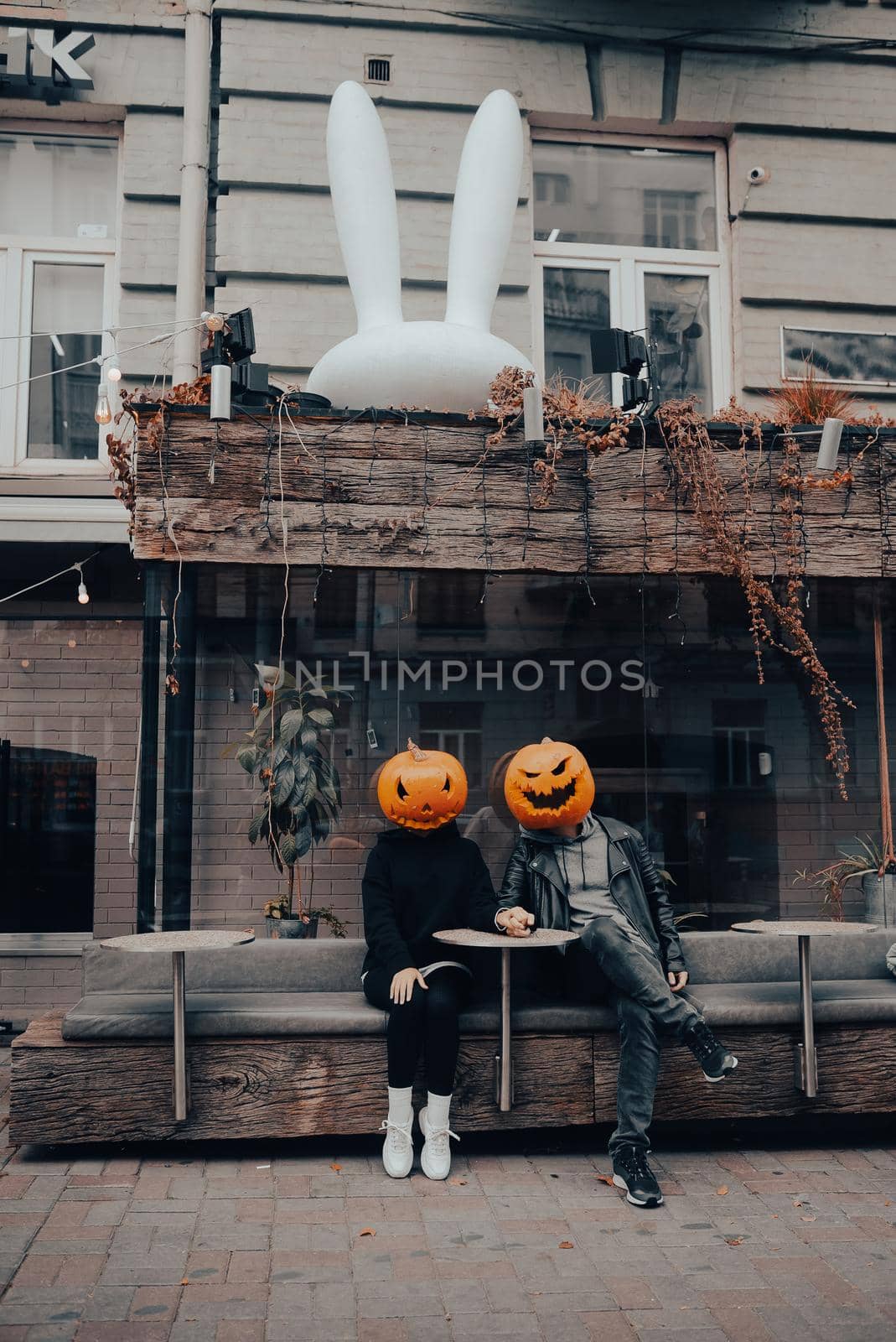 Guy and girl with pumpkin heads in a street cafe. Halloween Concept