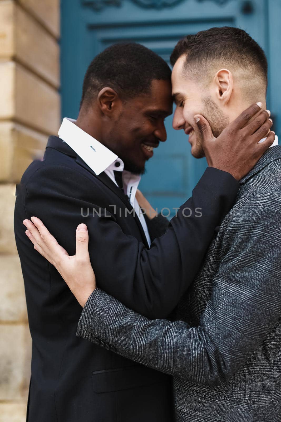 Afro american handsome man hugging caucasian boy in door background. same sex couple by sisterspro