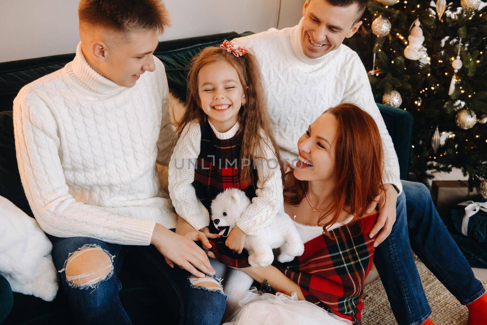 Close-up portrait of a happy family sitting on a sofa near a Christmas tree celebrating a holiday.