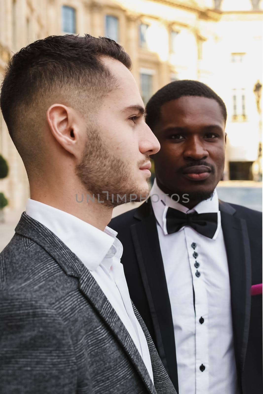 close up portrait of same sex couple. caucasian man wearing suit standing near afro american boy. Concept of business and male fashion.