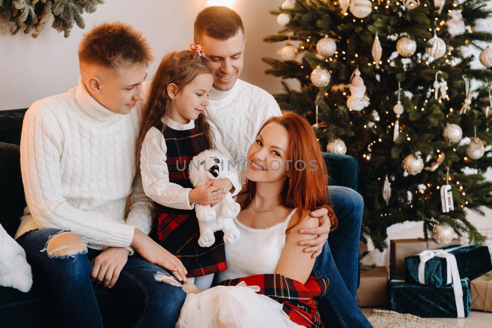 Close-up portrait of a happy family sitting on a sofa near a Christmas tree celebrating a holiday.