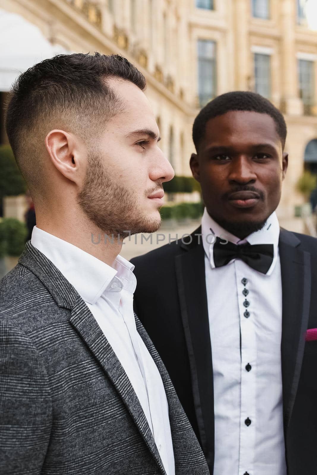 close up portrait of same sex couple. caucasian man wearing suit standing near afro american boy. Concept of business and male fashion.