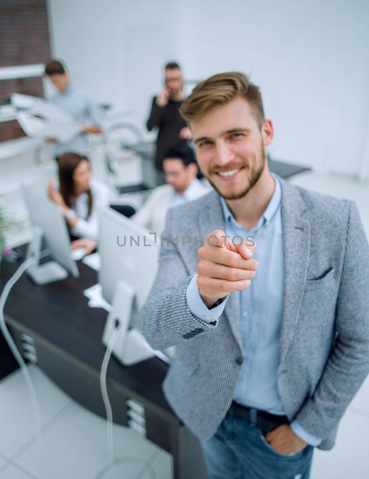 young businessman standing in the office and pointing at you by asdf