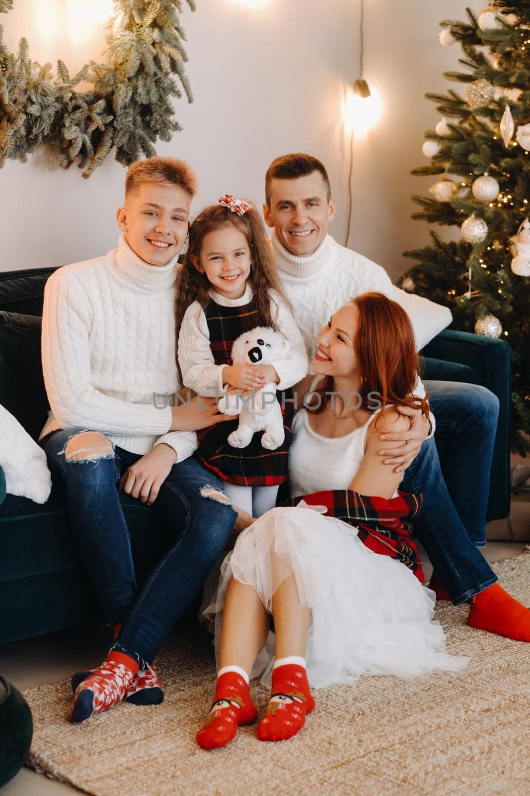 Close-up portrait of a happy family sitting on a sofa near a Christmas tree celebrating a holiday by Lobachad