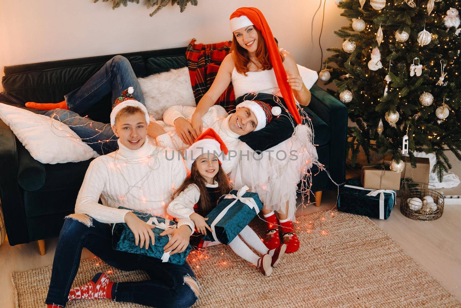 Close-up portrait of a happy family sitting on a sofa near a Christmas tree celebrating a holiday.