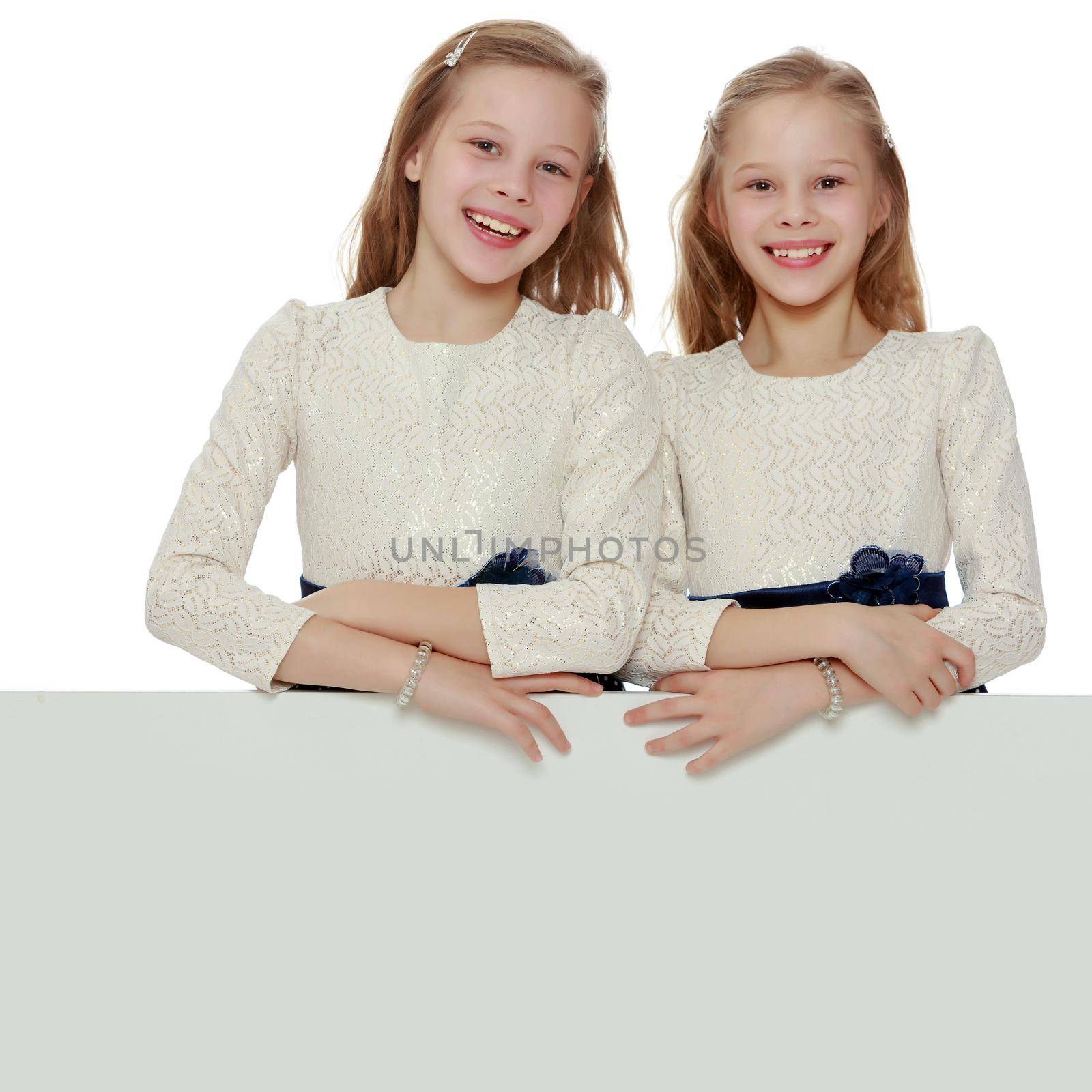 Two little girls peeking out from behind a white advertising ban by kolesnikov_studio