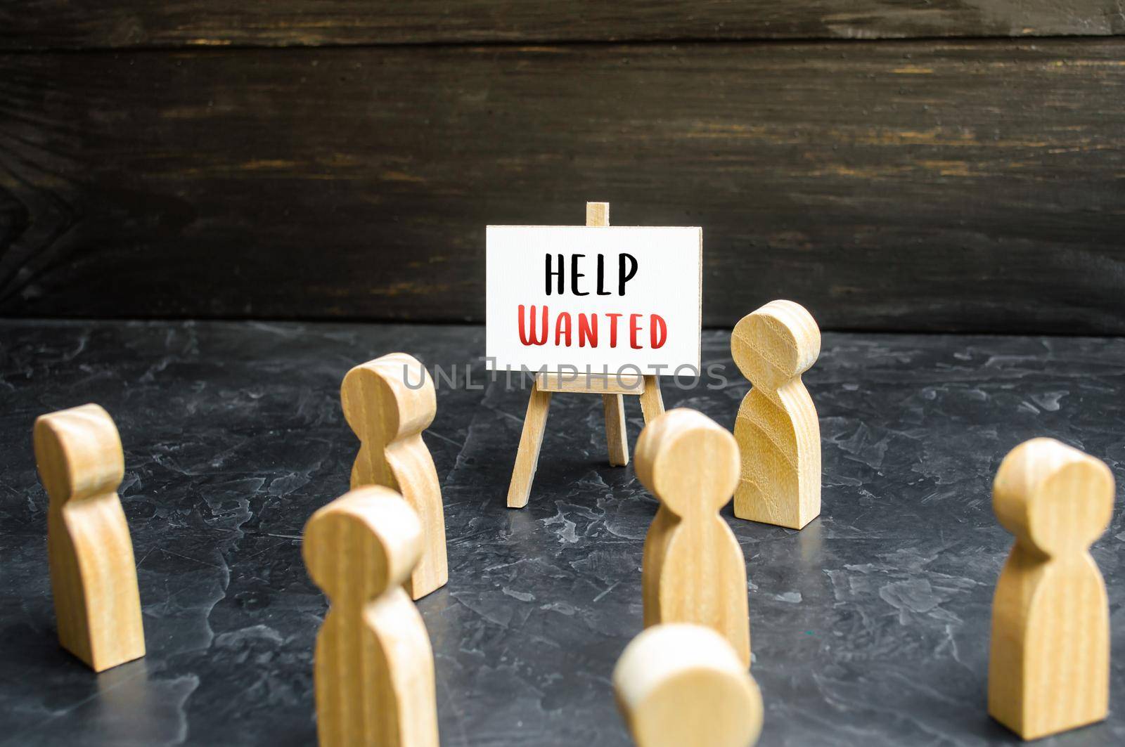 A man with a Help Wanted sign appeals to the crowd about hiring. Call for help, volunteering. Search and recruitment of new employees for work. Hire staff. Employment Agency. Recruiting, staffing.