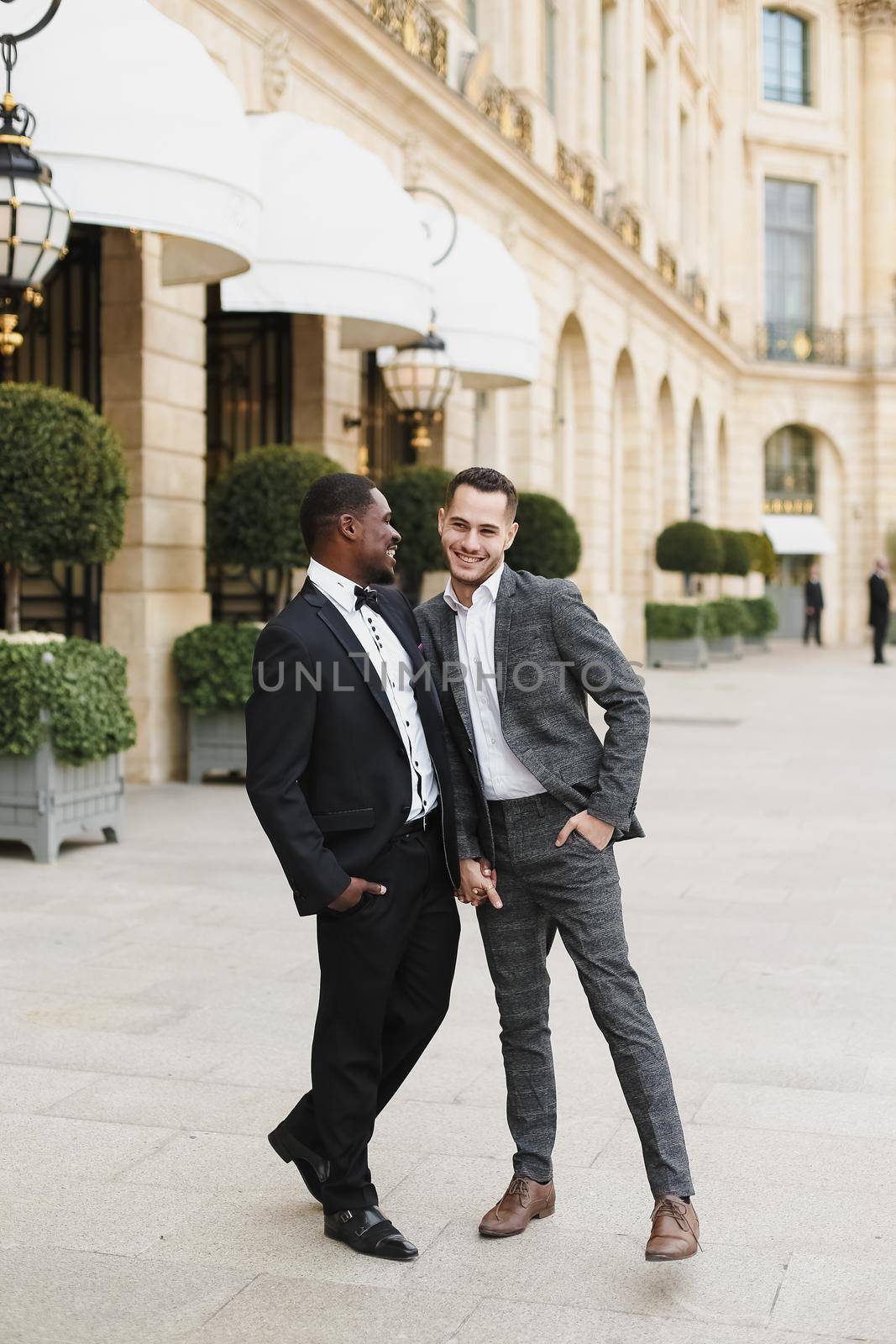 Afro american and caucasian stylish gays walking outside in city. Concept of same sex male couple.