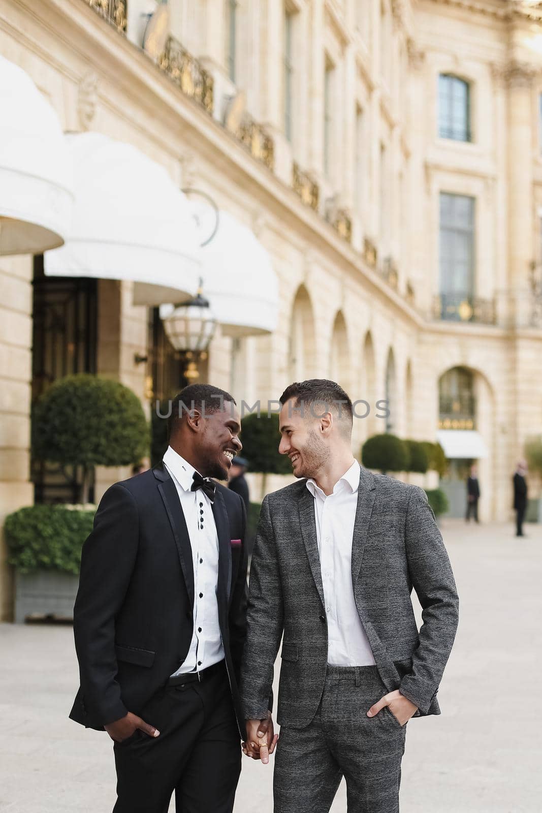 Afro american and caucasian happy handsome gays walking outside and holding hands. by sisterspro