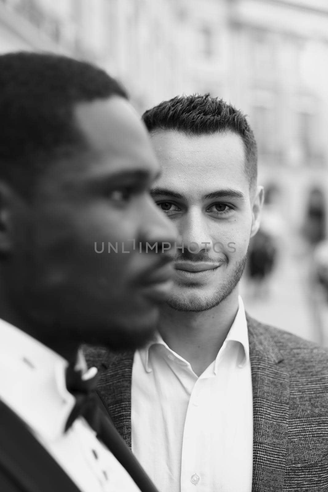 Focus on caucasian man wearing suit standing near afro american male person. Black and white bw portrait in Paris by sisterspro