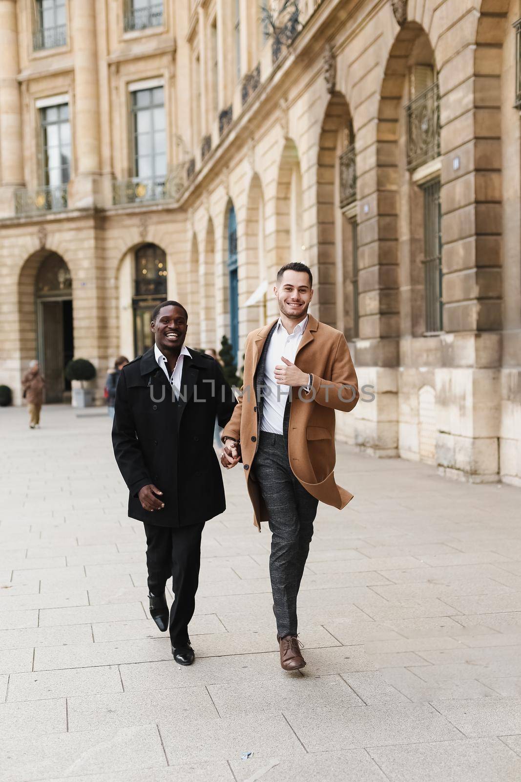 Caucasian smiling man in suit walking with afroamerican male lgbt gay and hugging in Paris France. by sisterspro