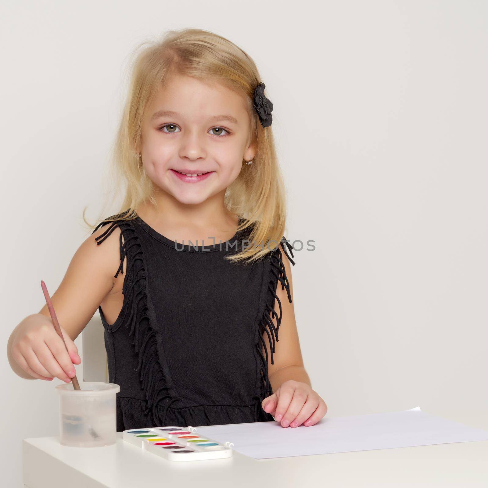 Joyful little girl draws with a brush and paints. The concept of children's creativity.