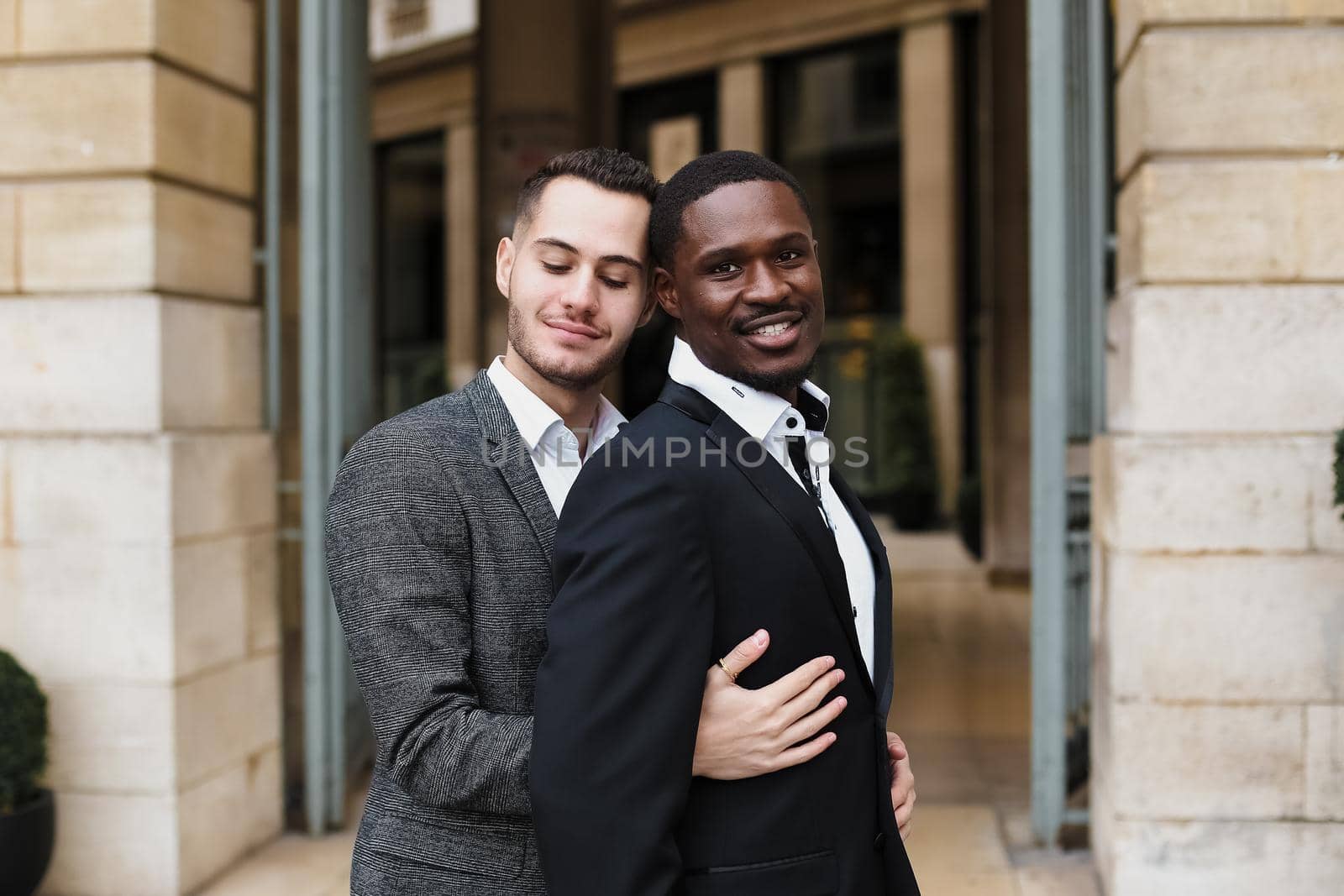 Portrait Caucasian man hugging afro american guy outside, same sex couple smiling by sisterspro