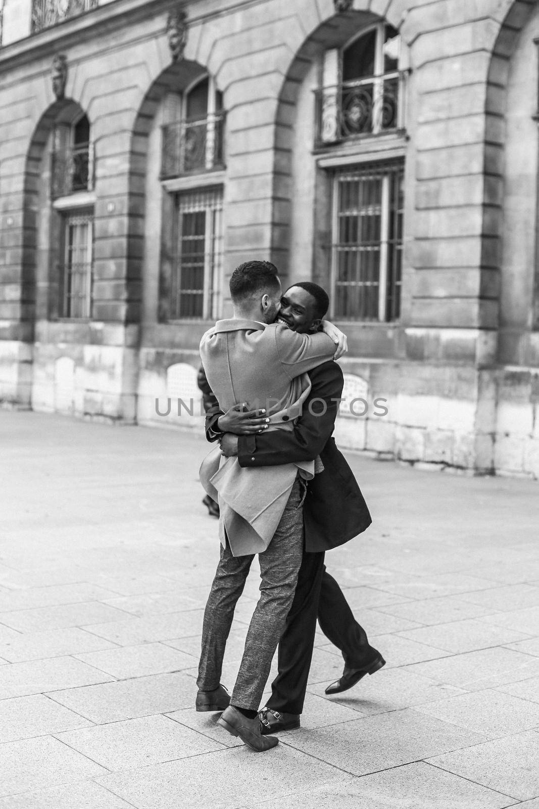 Black and white bw portrait Caucasian man running with afroamerican male person and holding hands in Paris by sisterspro