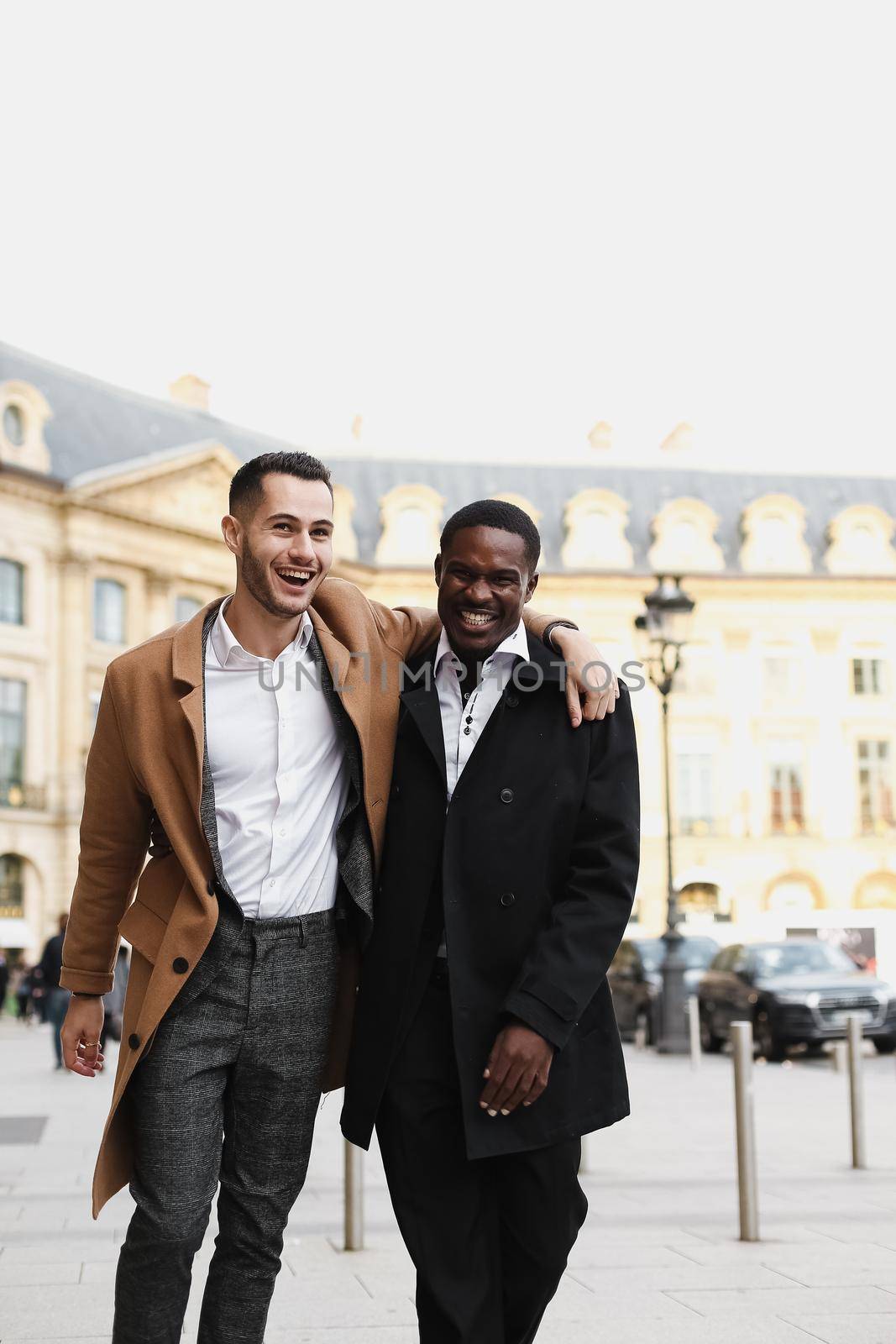 Caucasian smiling man in suit walking with afroamerican male lgbt gay and hugging in Paris France. by sisterspro