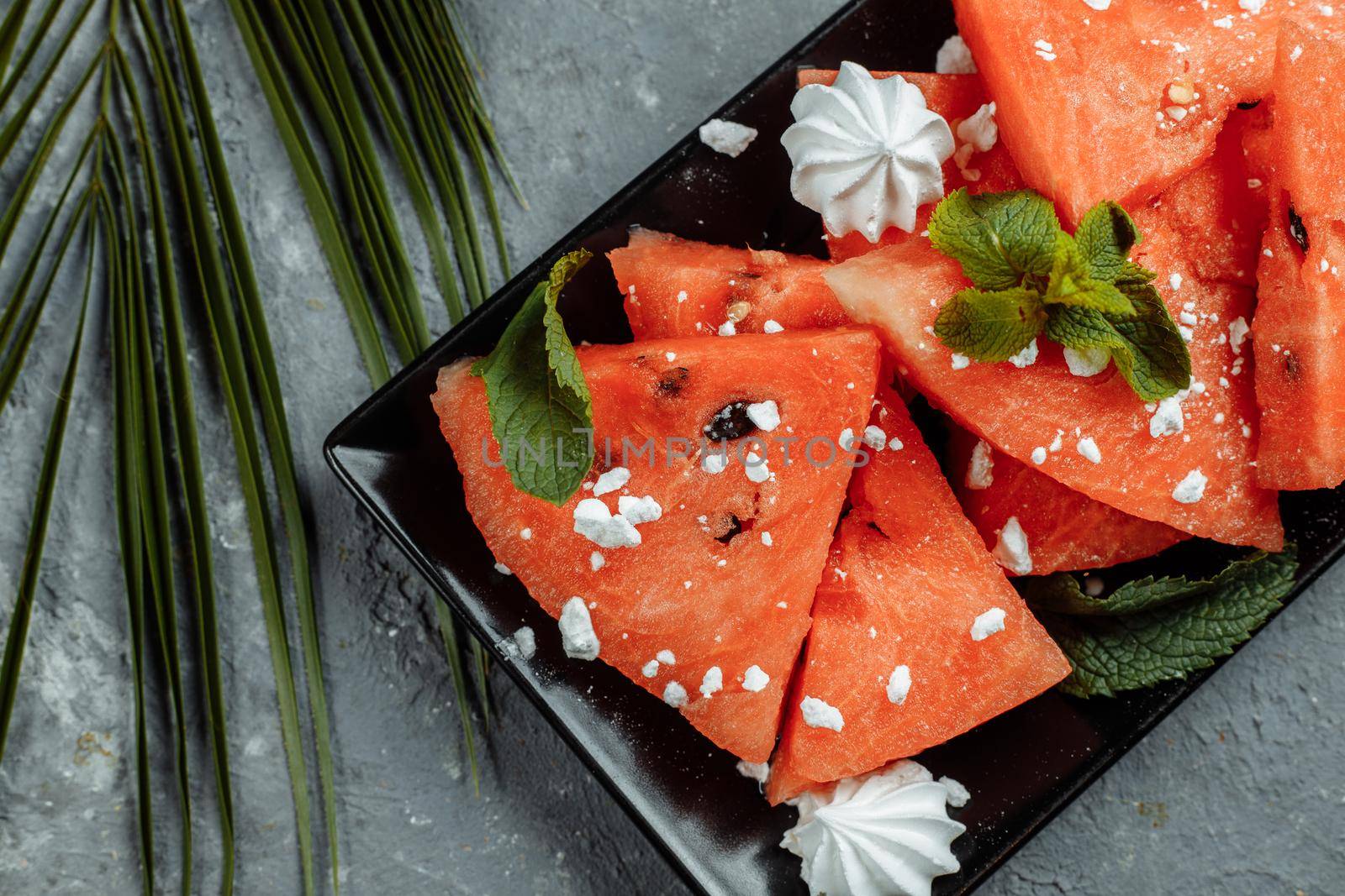 Pieces of fresh red watermelon on a black plate.