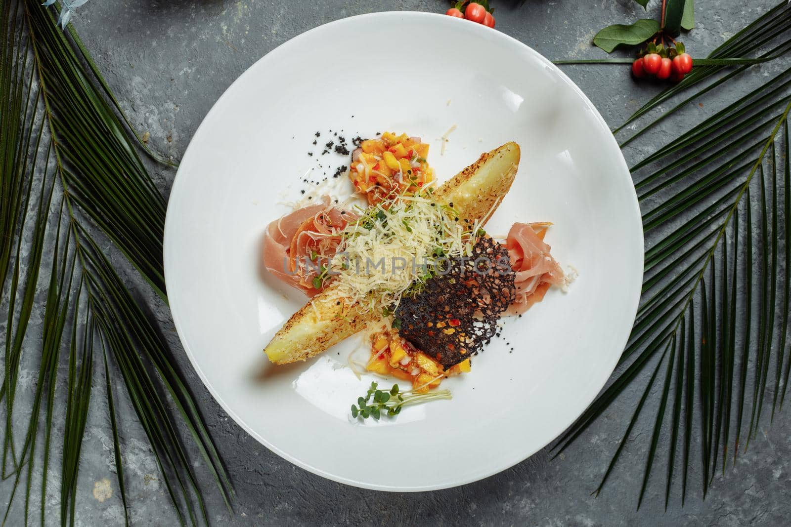 baked melon with parmesan and jamon on a white plate.