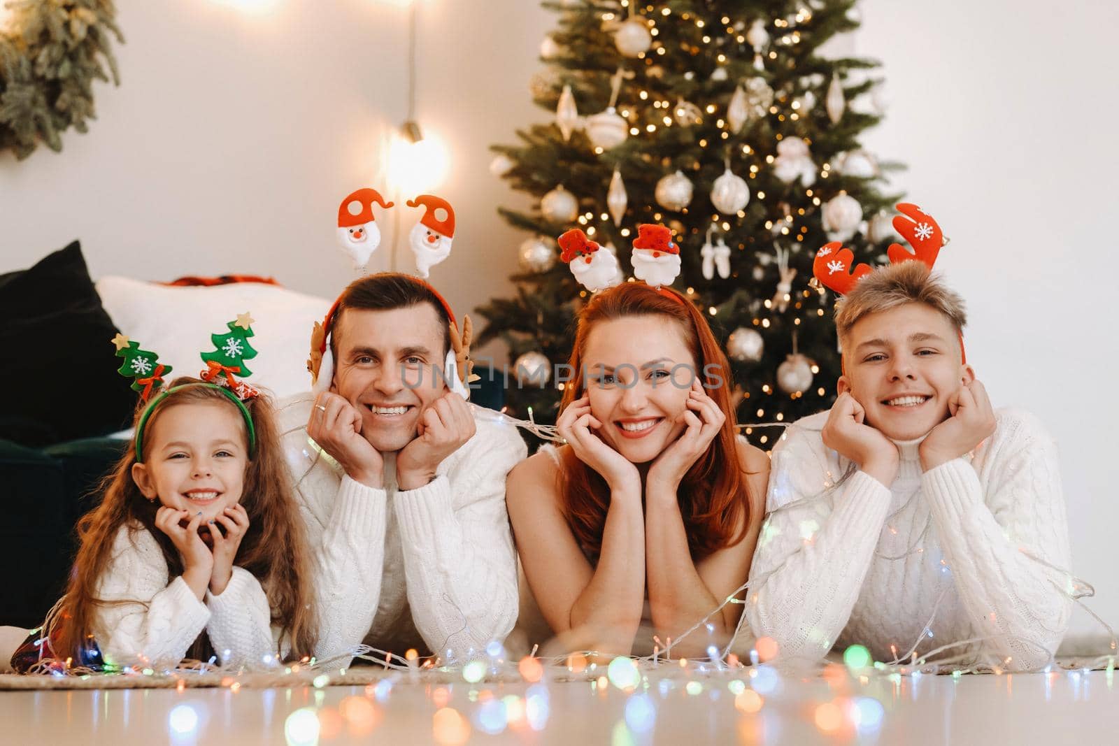 Close-up portrait of a happy family lying near a Christmas tree celebrating a holiday.