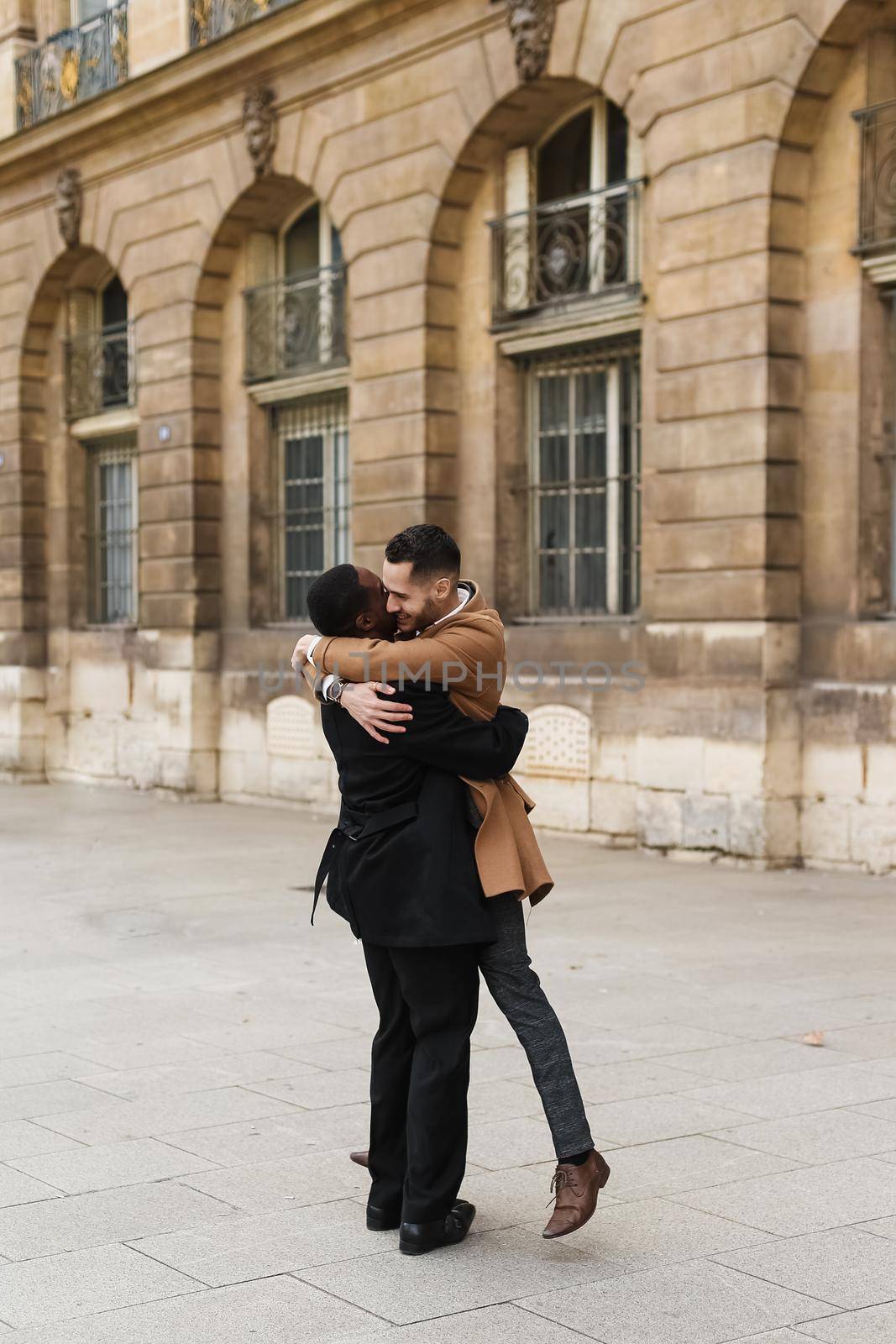 Caucasian smiling man in suit walking with afroamerican male lgbt gay and hugging in Paris France. by sisterspro