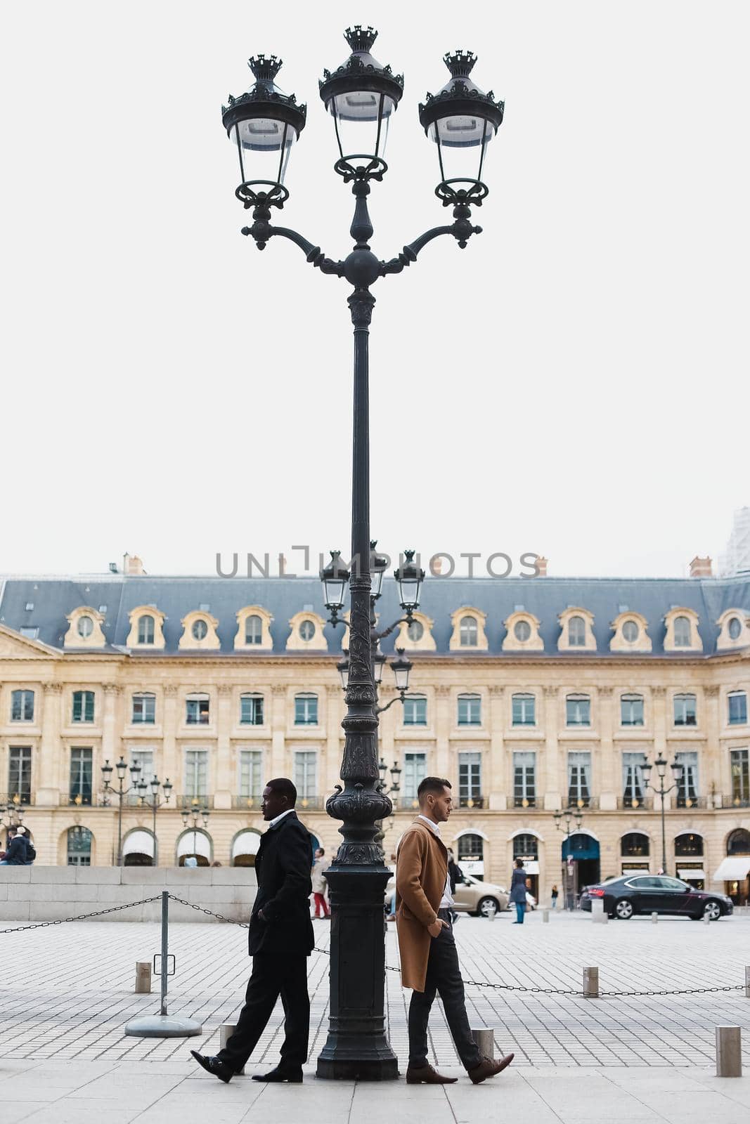 Afro american and caucasian men standing near street lantern in city. by sisterspro