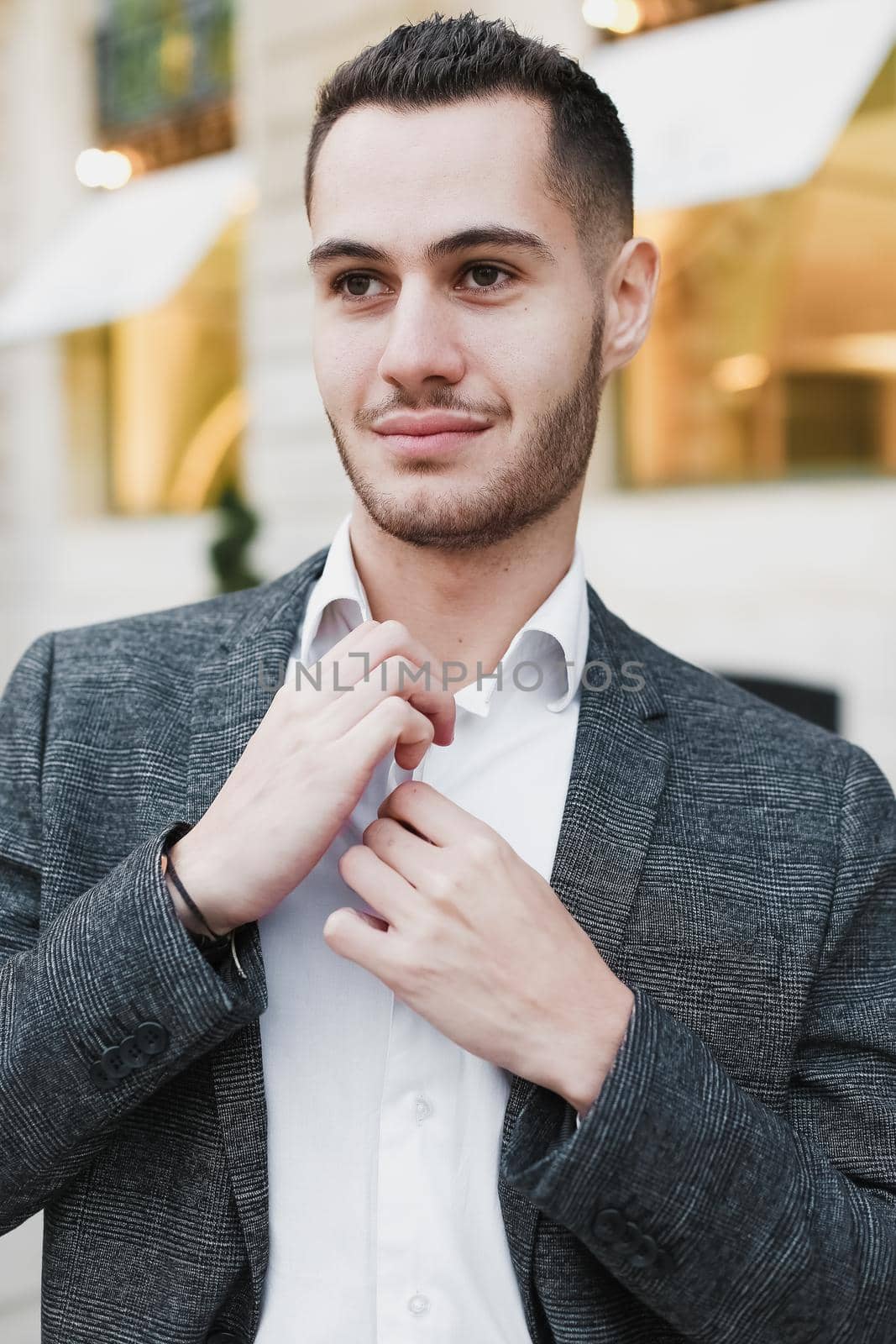 Young cacuasian male person wearing suit standing near building outdoors. Concept of fashion and businessman, urban life.