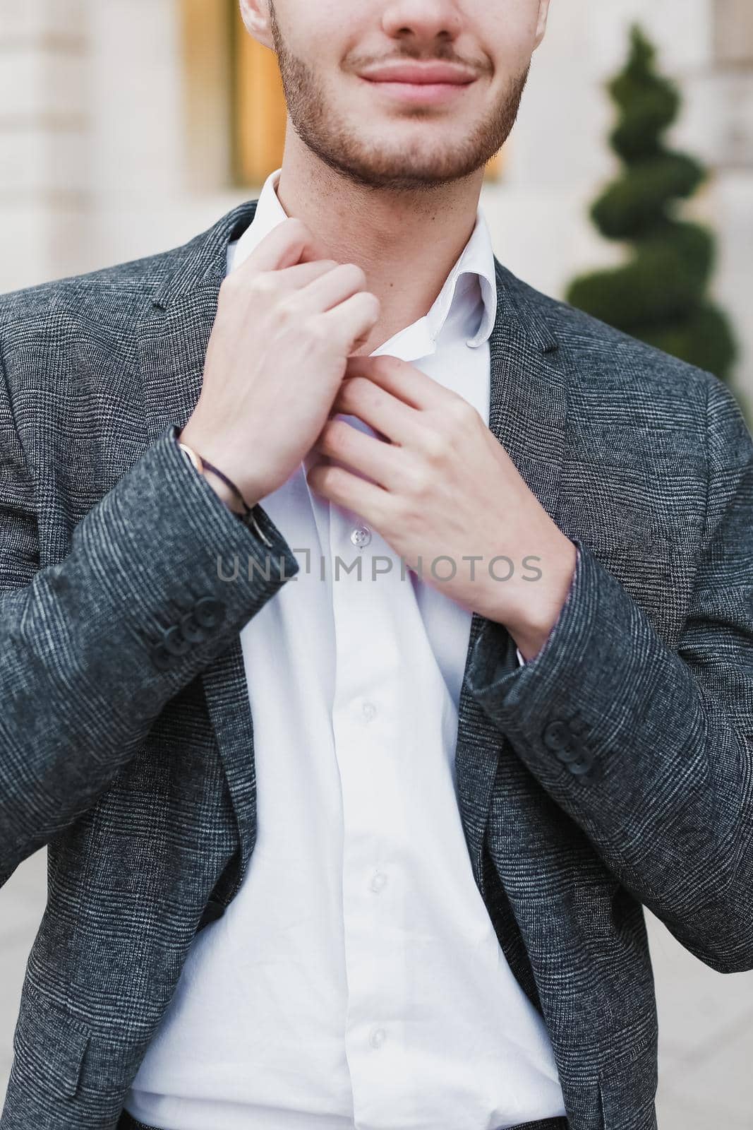 Young cacuasian male person wearing suit standing near building outdoors. Concept of fashion and businessman, urban life.