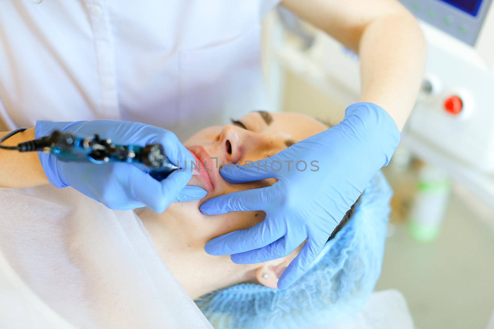 Close up hands in latex gloves making lip tattoo with microblading device. Concept of beauty salon, permanent makeup and cosmetology equipment.