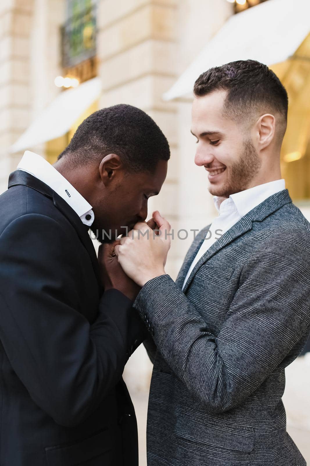 close up portrait of afro american man kissing caucasian boy hands. by sisterspro