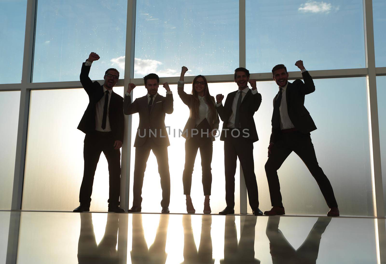 a team of professionals rejoices in a modern city office with a panoramic window.