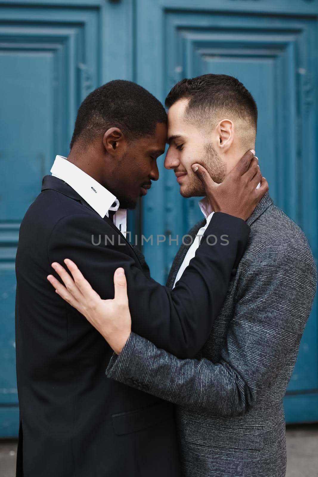 Afro american handsome man hugging caucasian boy in door background. same sex couple by sisterspro