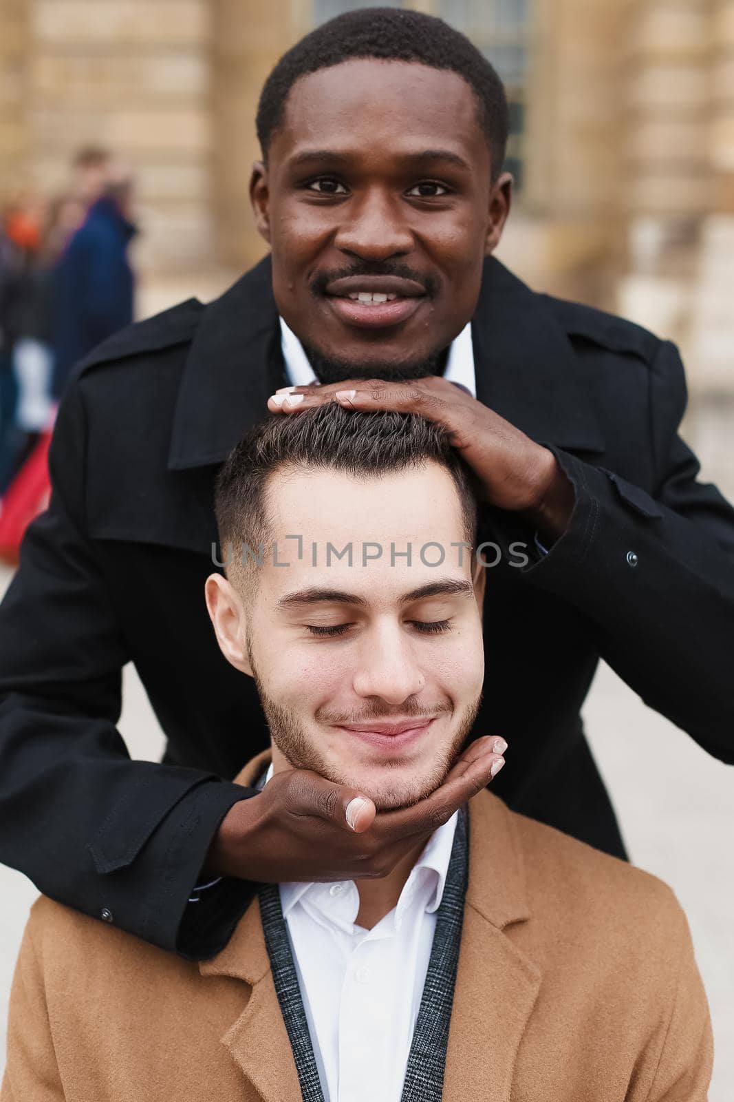 Afro american boy holding caucasian guy head by hands. by sisterspro