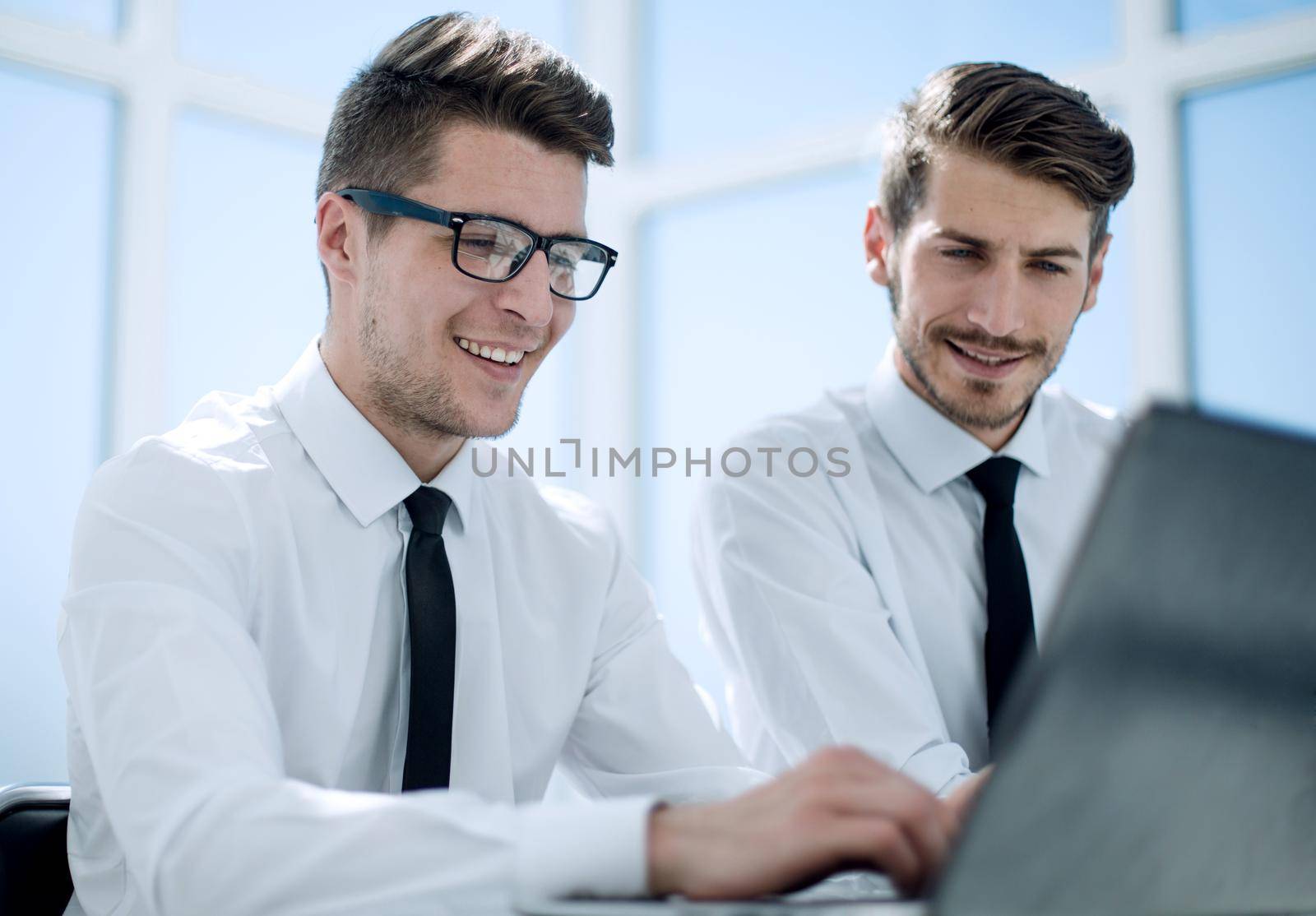 Close-up of happy smiling businessman or employer working on digital laptop in modern office interior