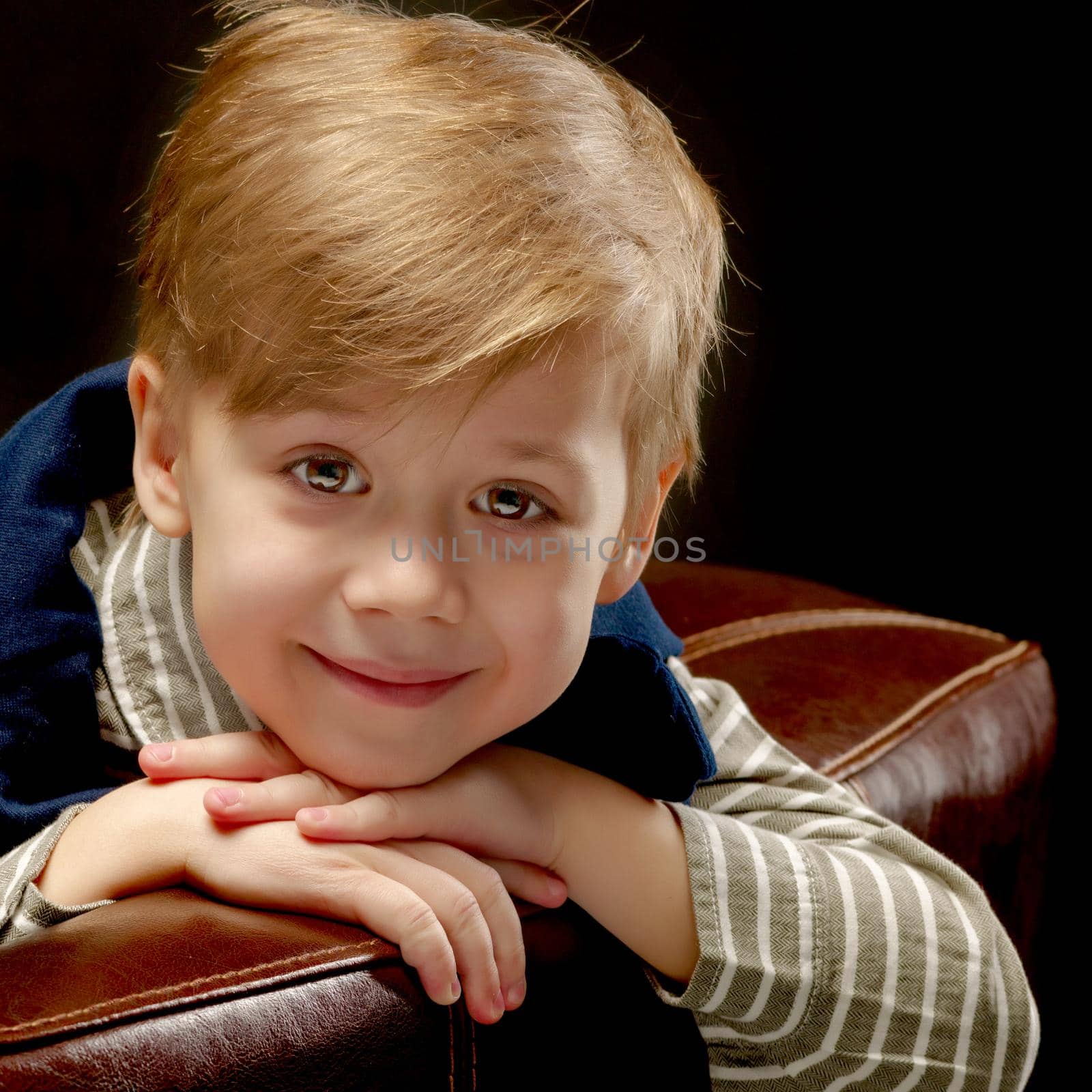 Beautiful little boy closeup. Studio portrait on black background. Concept layout for magazine cover.