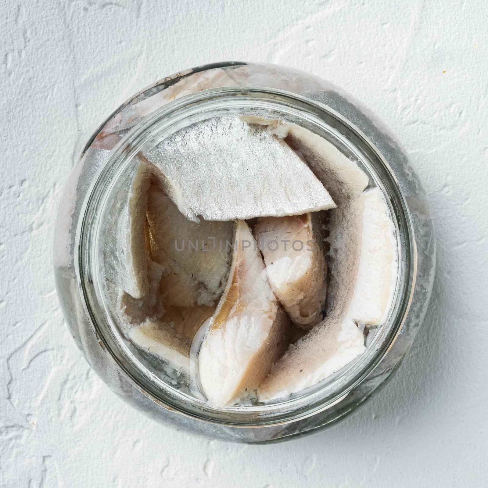 Canned Herring , fish preserves, in glass jar, on white background, top view flat lay, square format by Ilianesolenyi