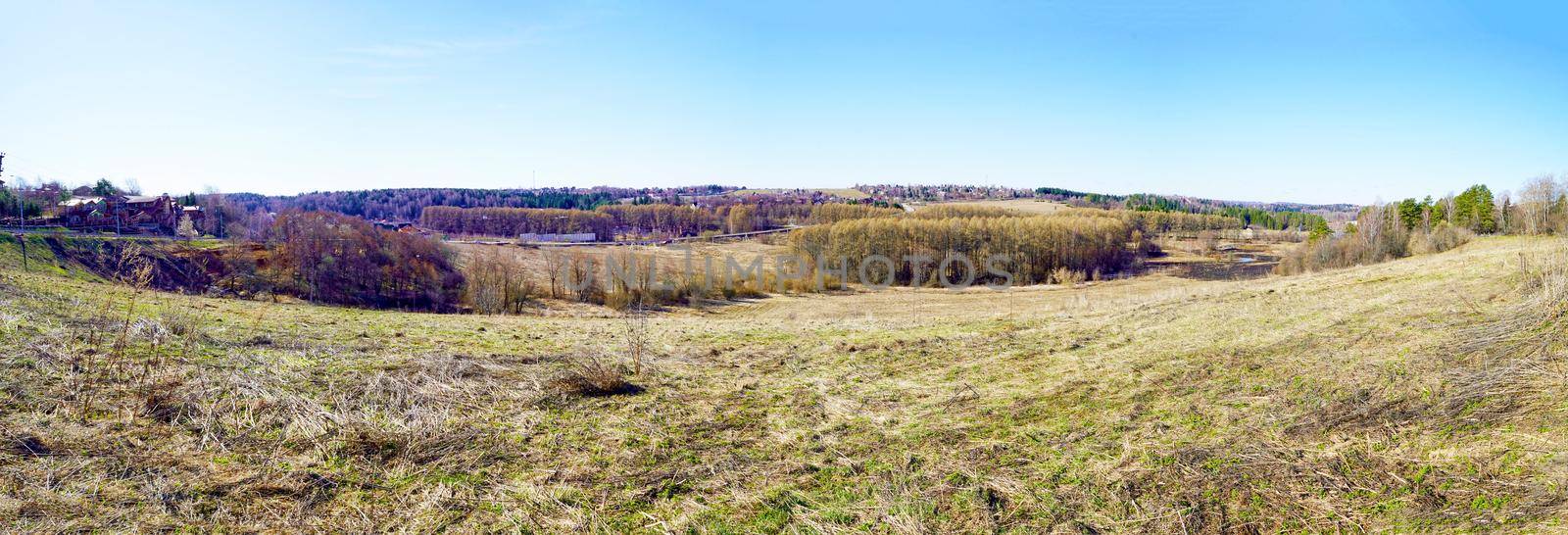 Panorama. A hilly landscape in early spring, when the grass is just beginning to turn green. Spring Russian landscape, Moscow region, Russia.