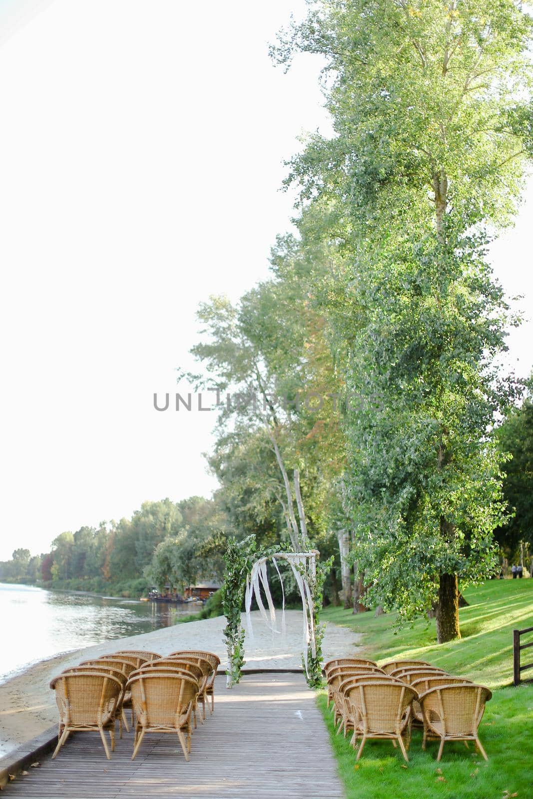 Birch wedding arch with wooden chairs in park. Concept of bridal celebration and place for ceremony.