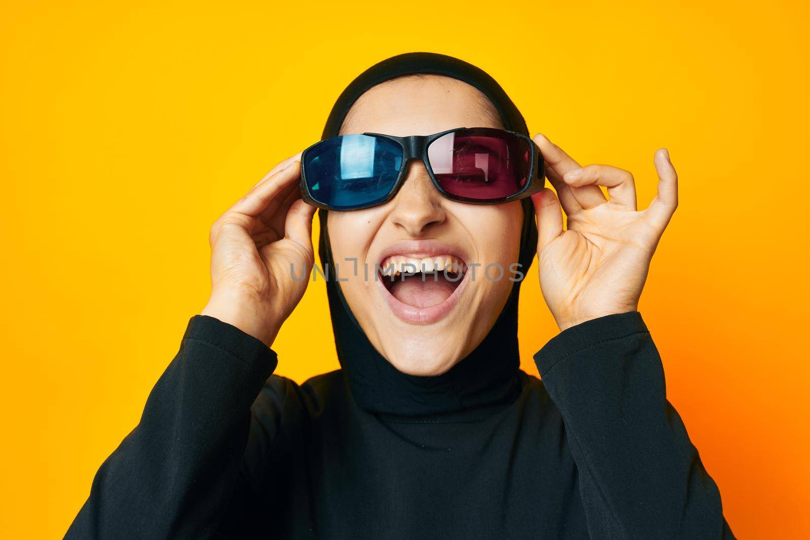 cheerful woman in black hijab popcorn 3D glasses cinema yellow background. High quality photo