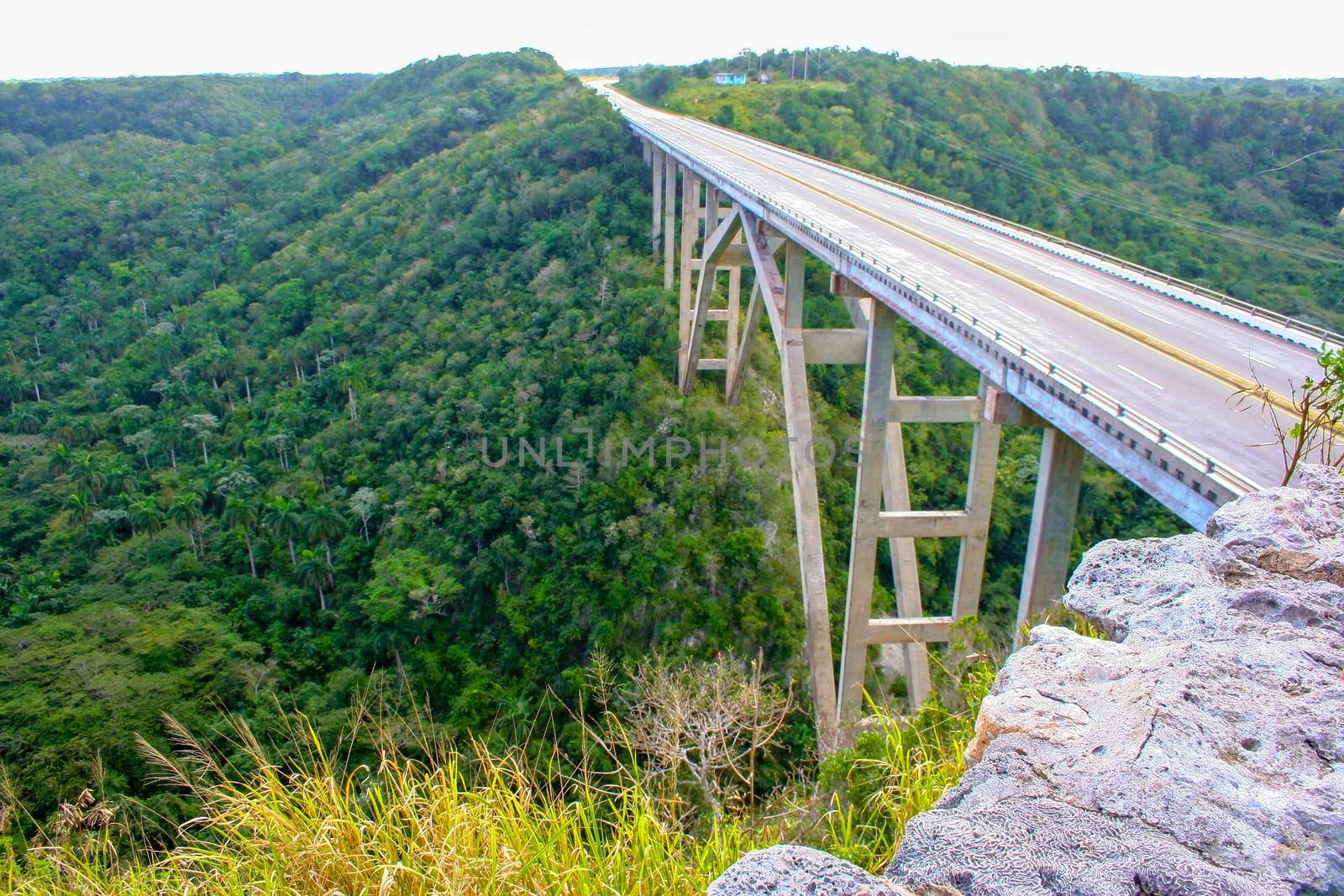Beautiful arched bridge over a deep gorge, among dense tropical vegetation. Republic of Cuba