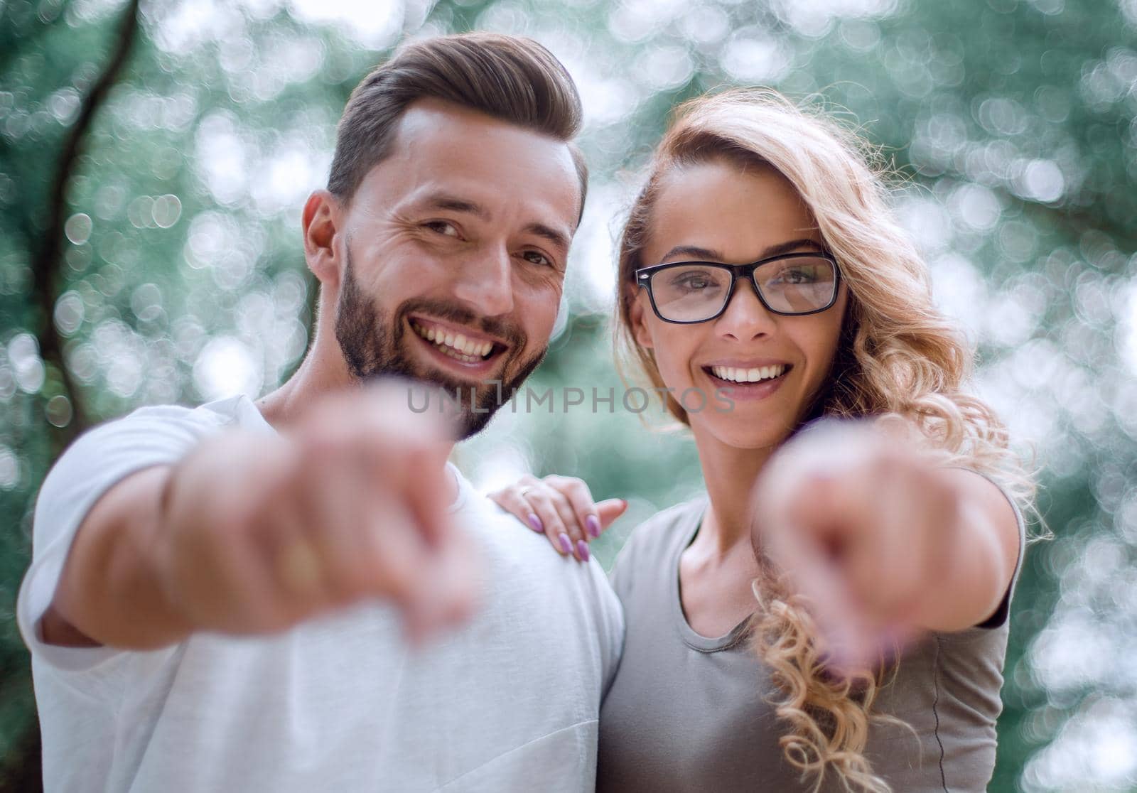 close up. smiling young couple pointing at you.