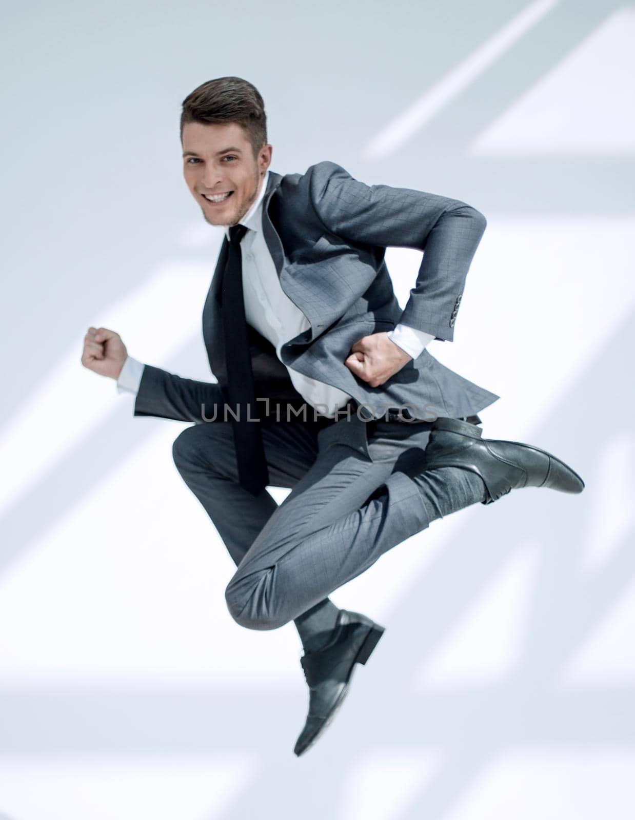 Full length portrait of a happy satisfied man in suitt jumping and looking at camera isolated over white background