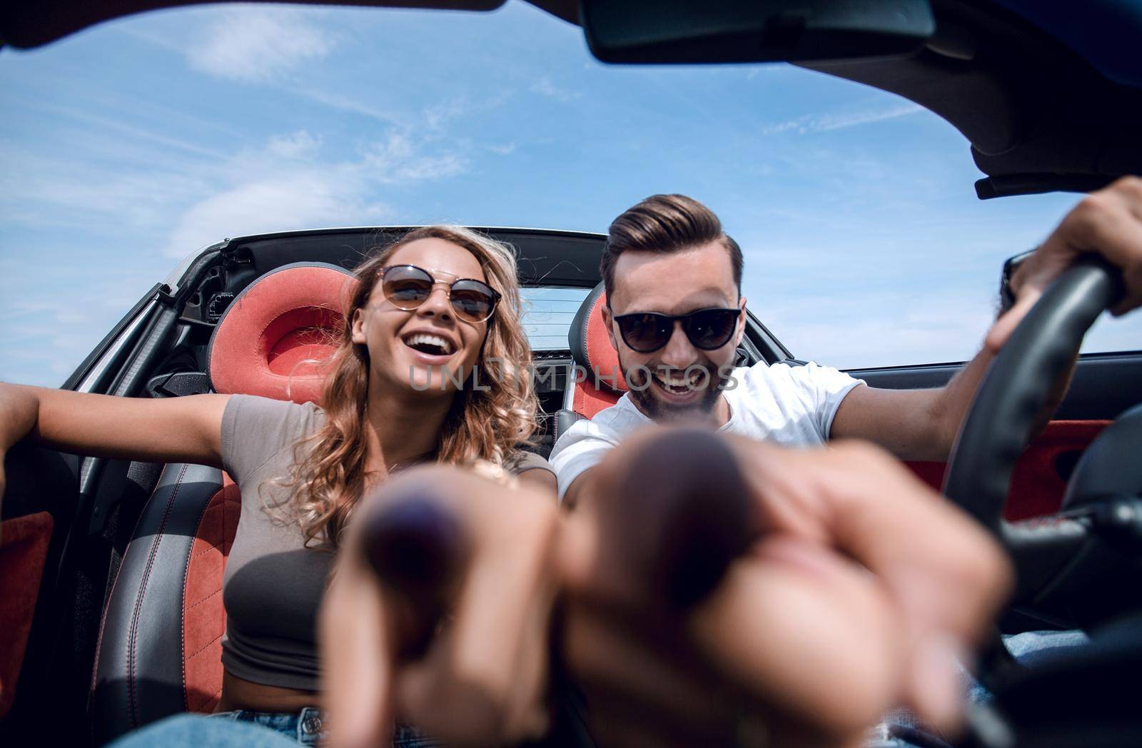 close up.young couple sitting in a convertible and pointing at y by asdf